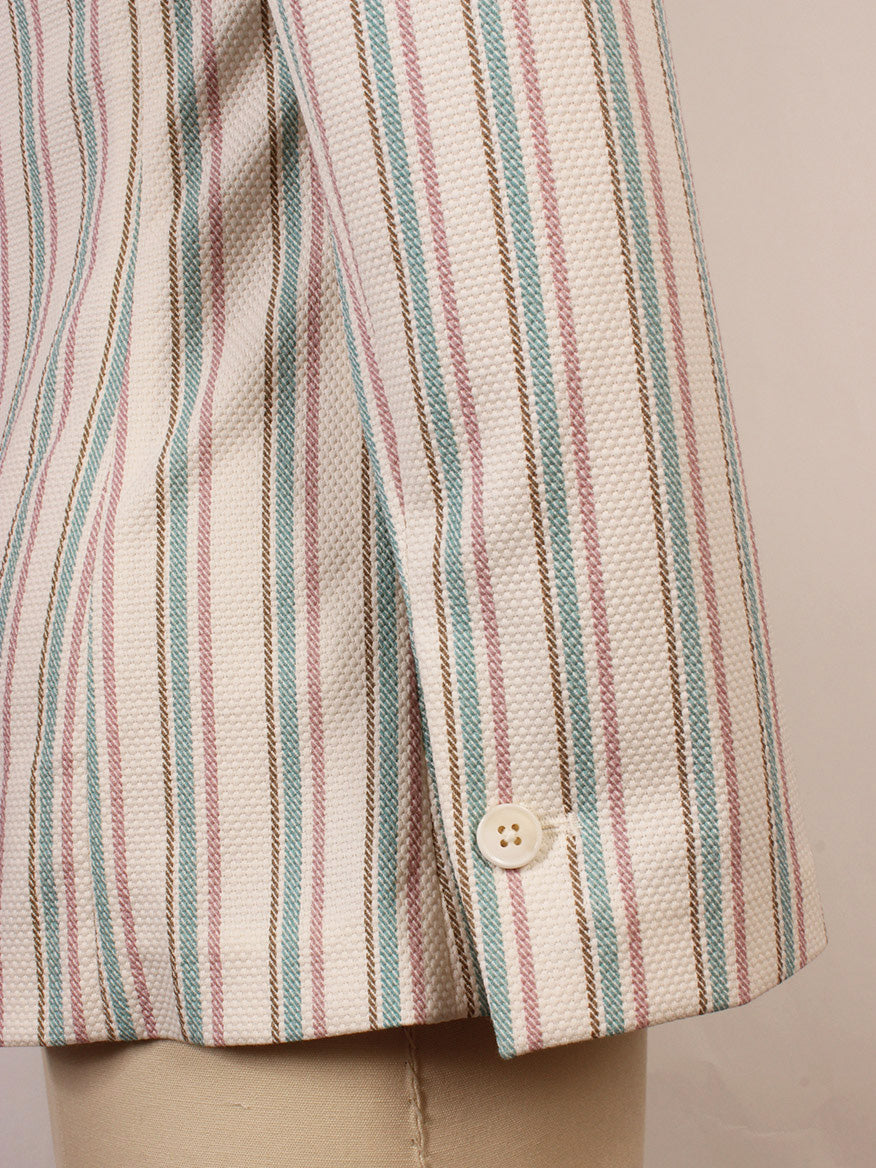 Close-up of a long-sleeve shirt cuff with vertical pink, blue, and brown stripes and a white button, styled under the Circolo 1901 1-Button Slim Stripe Jacket in Laguna with jetted pockets and classic notch lapels on a mannequin.