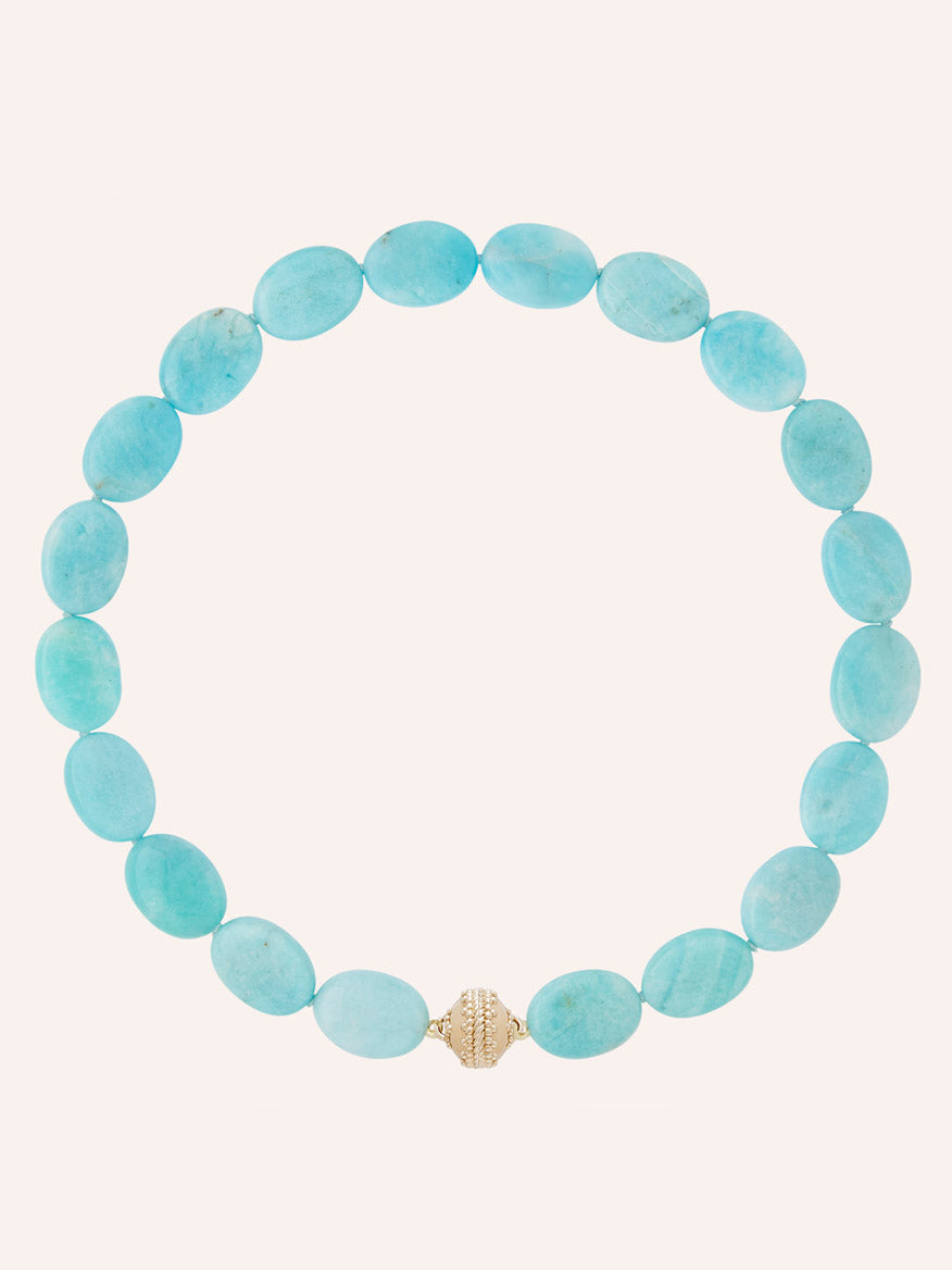 The Clara Williams Amazonite Flat Oval Necklace, featuring flat oval amazonite beads and finished with a 14K gold clasp, is arranged in a circle on a plain light background.