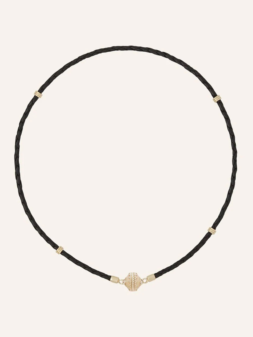 The Clara Williams Aspen Braided Leather Black Mini Necklace features a black braided leather design with gold vermeil accents and a secure sterling silver clasp, displayed on a plain light background.