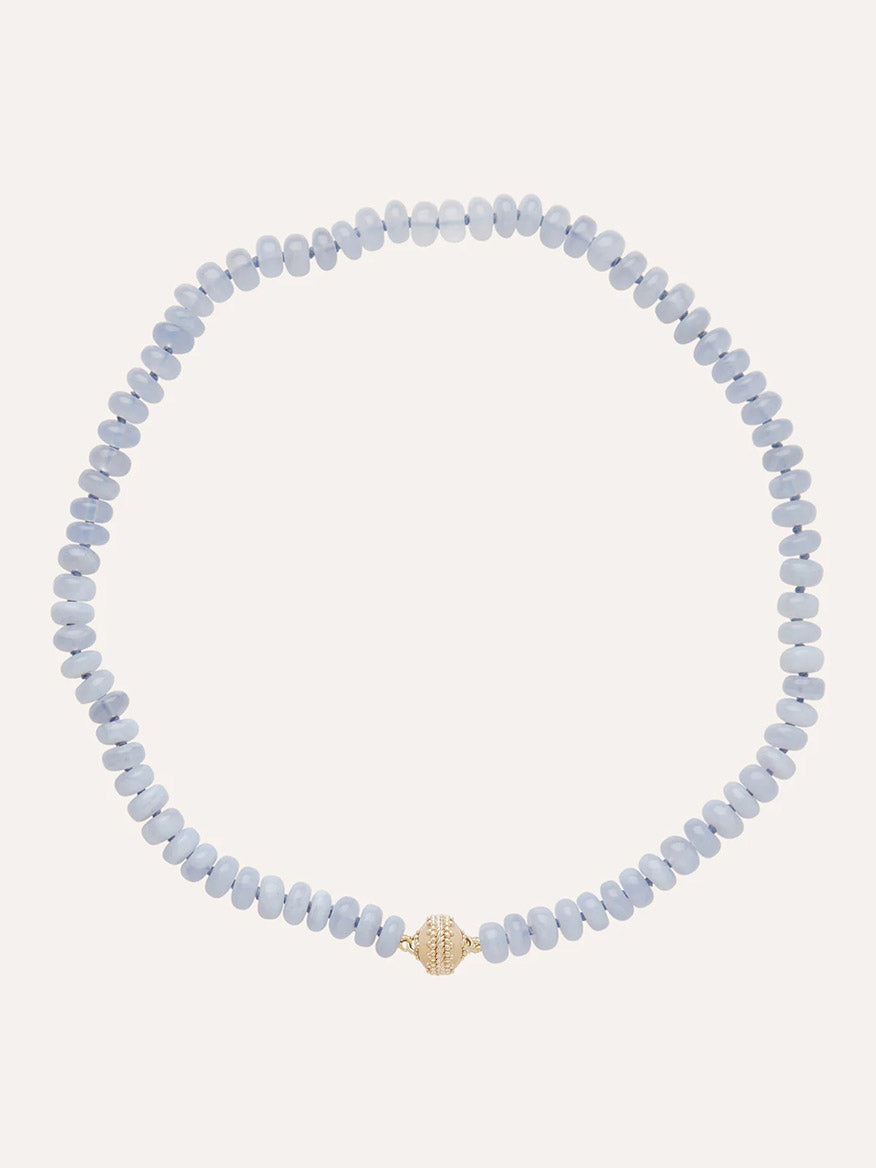 The Clara Williams Chalcedony Rondelle Mini Necklace showcases light blue Blue Chalcedony rondelle stones with a single textured 14K yellow gold bead at the center, displayed on a plain background.