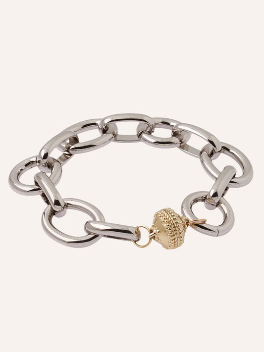 The Clara Williams Gold Coast Rhodium Bracelet features large oval links, chunky rhodium plating, and a bold 14K yellow gold ClaraClasp, shown against a light background.