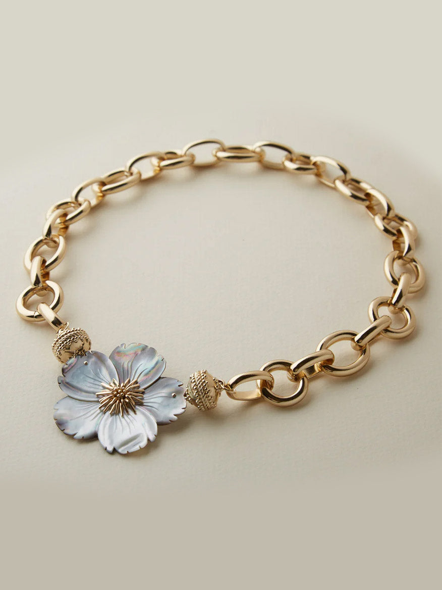 The Clara Williams Gold Coast Necklace in 14K yellow gold features oval links, a decorative flower pendant, two textured round beads, and is finished with the signature ClaraClasp.