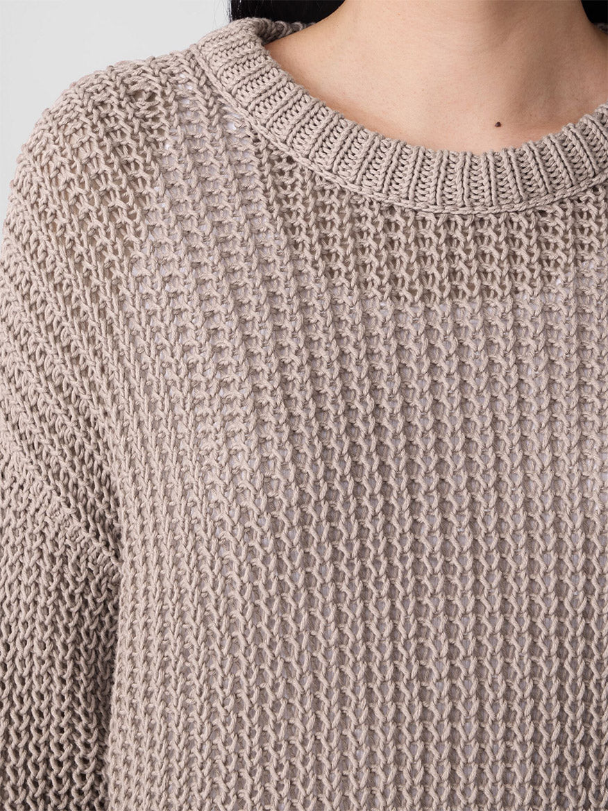 Close-up of a person wearing the Eileen Fisher Peruvian Organic Cotton Cord Crew Neck Top in Wheat, featuring a chunky knit, boxy fit, and round neckline. Only the lower face, neck, and upper chest are visible.