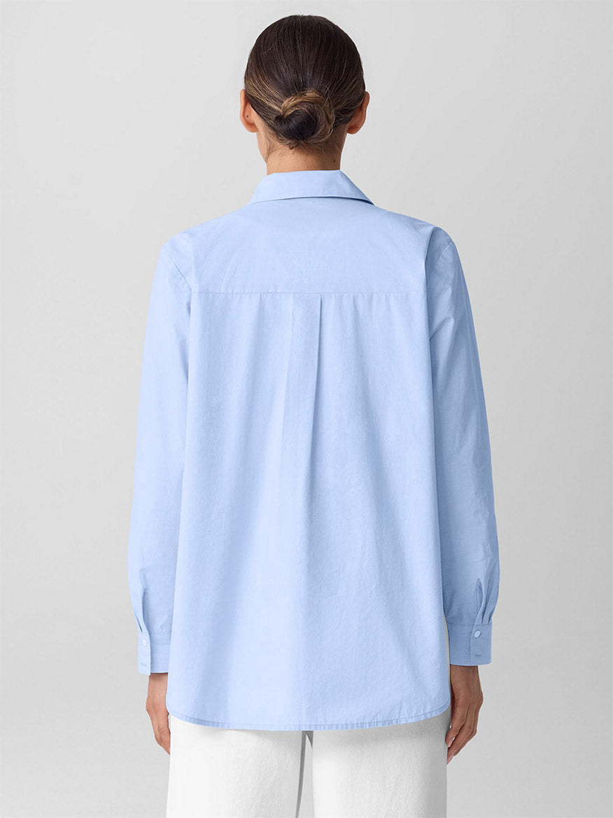 A person with their hair in a low bun is wearing the Eileen Fisher Striped Poplin Classic Collar Shirt in Myrtle and white pants, shown from the back against a plain background.