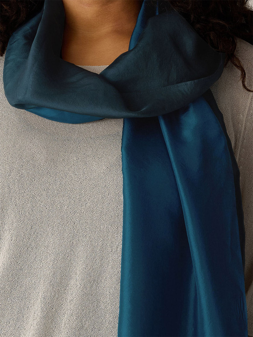 A person wearing the Eileen Fisher Watercolor Organic Silk Scarf in Sailor Blue, draped over a light gray textured top.