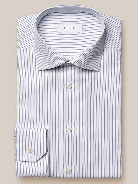 A neatly folded, long-sleeved, Eton Navy Blue Fine Striped Cotton-Tencel® Shirt in white with thin blue vertical stripes. This cotton-tencel shirt features a collar and buttoned cuffs, and the label reads "ETON".