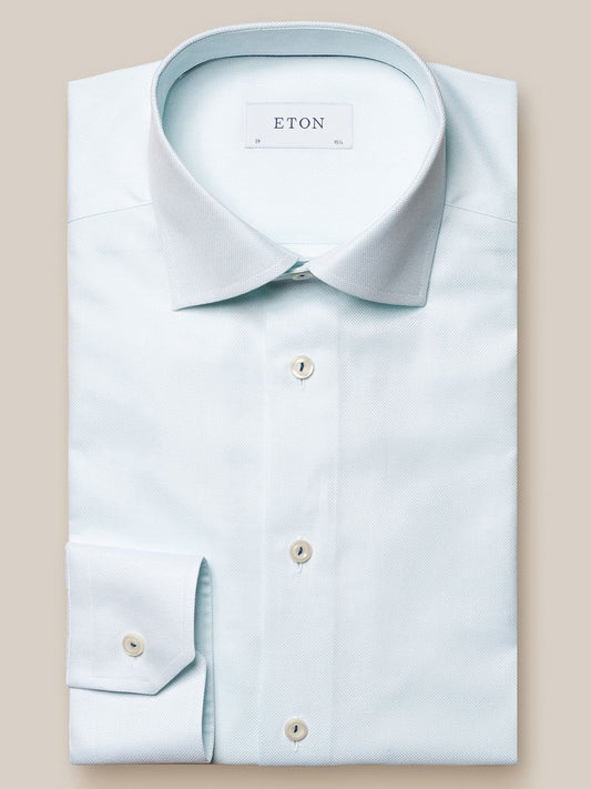 A pale blue Eton Green Dobby dress shirt displayed flat, showcasing its pointed collar, button closure, and folded left cuff.