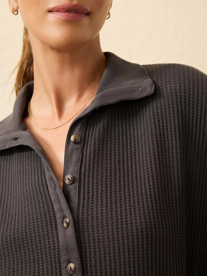 Close-up of a woman wearing the Faherty Brand Après Waffle Henley in Washed Black, featuring a relaxed fit, waffle texture, collar, and paired with a delicate gold necklace.