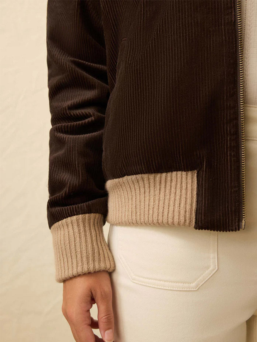 A person wearing the Faherty Brand Heritage Cord Jacket in Chocolate Brown with beige ribbed cuffs and off-white pants—shown from shoulder to hip, it’s a perfect casual jacket look for fall.