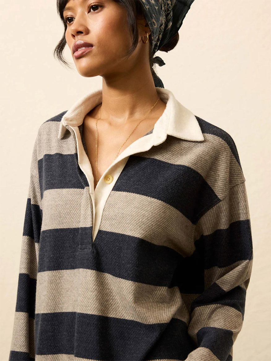 A person wearing the Faherty Brand Legend™ Sweater Rugby Popover in Navy Rugby, featuring ultra-soft fabric and a collared neckline, with a headscarf, glances to the side against a neutral background.