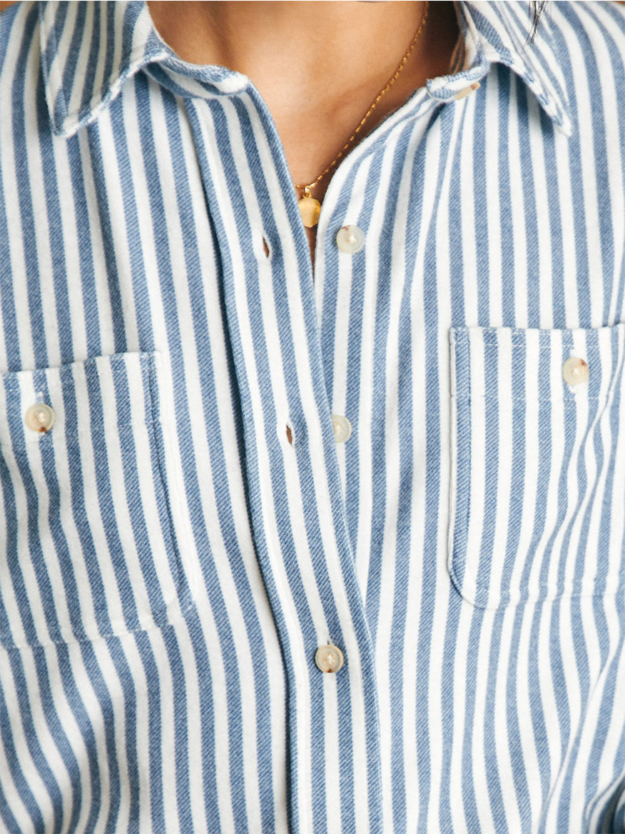 Close-up of a person wearing a blue and white striped Faherty Brand Legend Sweater Shirt in Navy Blazer Stripe with buttons.