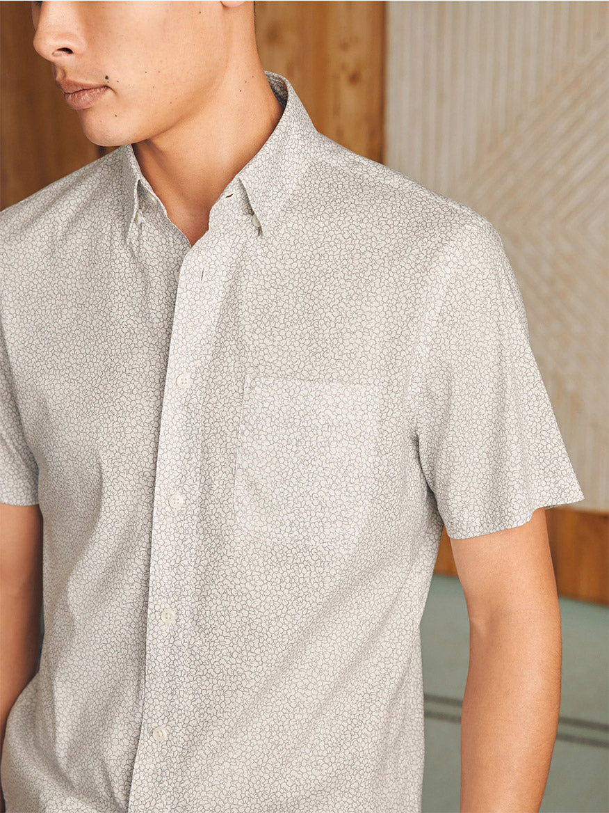 Close-up of a young man wearing a Faherty Brand Movement Short-Sleeve Shirt in Ivory Cliff Floral, focusing on the collar and upper chest area.