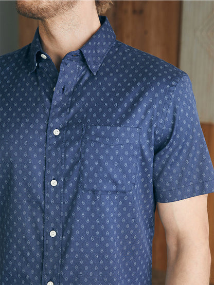 Close-up of a man wearing a Faherty Brand Movement Short-Sleeve Shirt in Navy Dusk Diamond Print with a buttoned-down collar and a front pocket. The focus is on the shirt and top part of his torso.