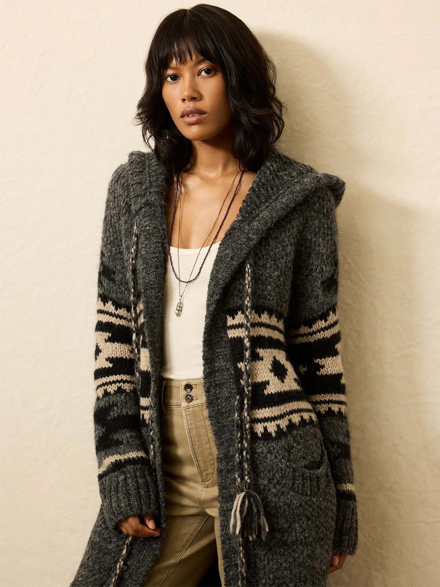 Woman wearing the Faherty Brand Steven Paul Judd Chahtah Hooded Duster in Charcoal Chahtah over a white top and beige high-waisted pants, standing against a plain light background.