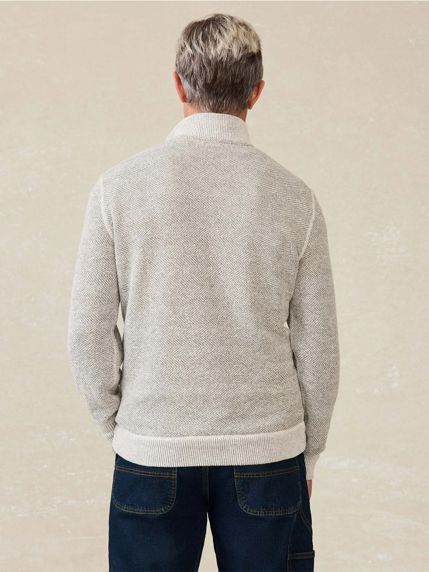 A person with short gray hair, wearing the Faherty Brand Whitewater Quarter Zip in Grey Shell Loop and dark blue jeans, stands with their back to the camera against a plain background.