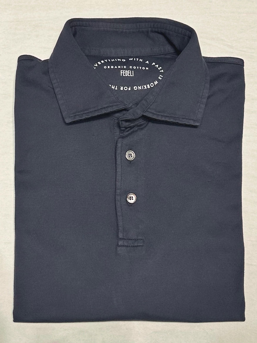 The Fedeli Zero Organic Cotton Short Sleeve Polo in Navy features a neatly folded dark navy design, a collar with three mother of pearl buttons, and the "FEDELI" brand label inside. Crafted from premium Giza organic cotton.
