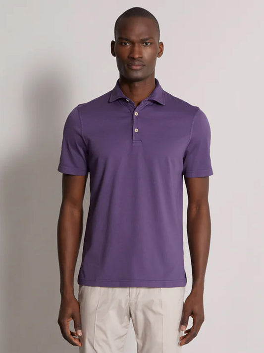A man in a Fedeli Organic Giza Cotton Polo in Grape and beige pants, standing with a neutral expression.