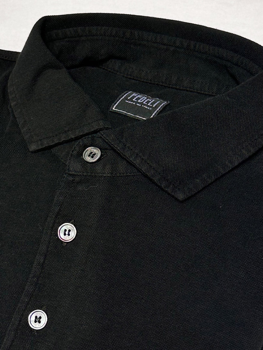Close-up of the Fedeli Zero Superlight Pique Short Sleeve Polo in Black, featuring three buttons and a visible “FREAKY” tag for a vintage-inspired look.