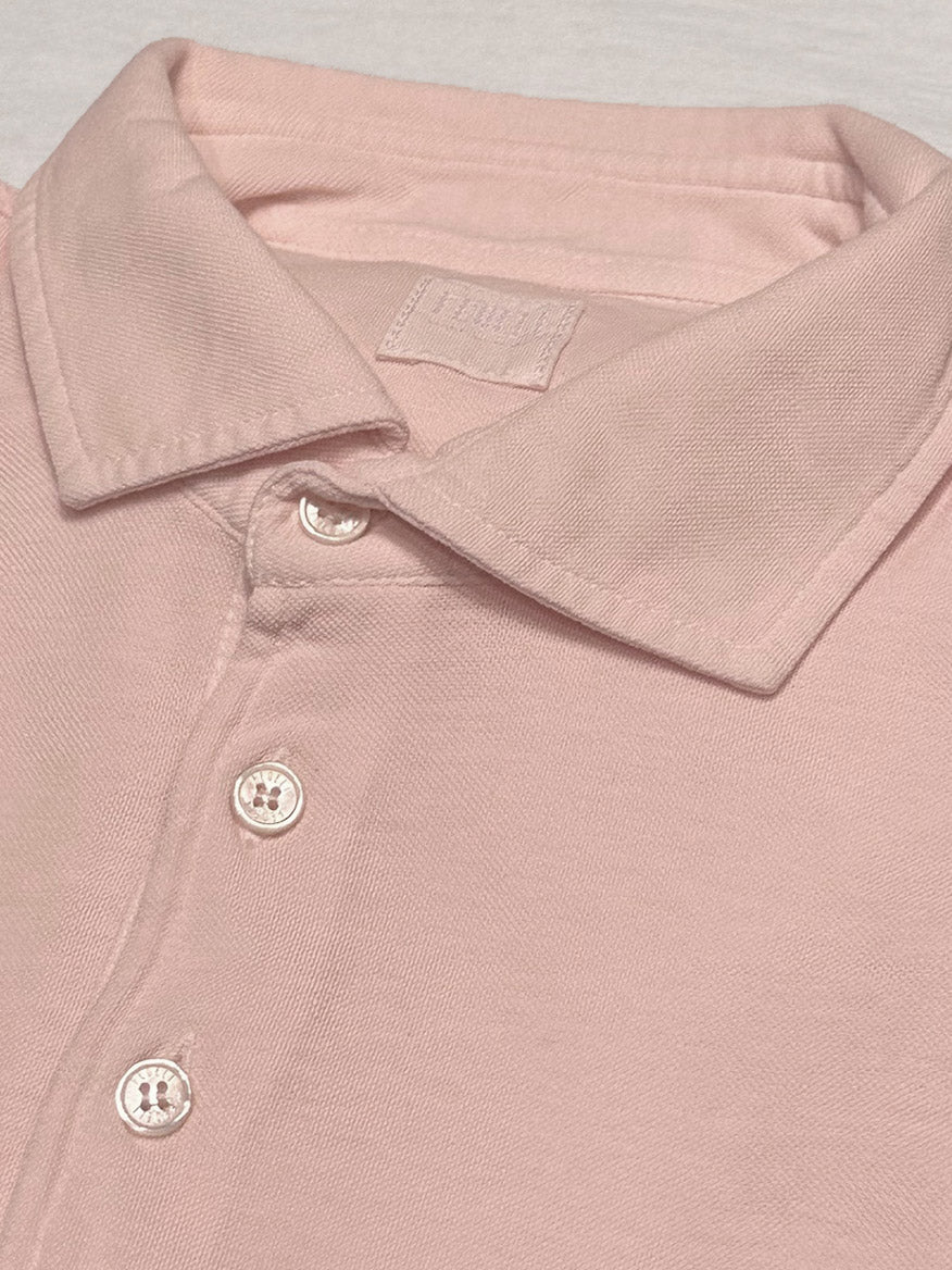 The Fedeli Zero Superlight Pique Short Sleeve Polo in Pink is folded neatly, highlighting vintage inspiration, Italian craftsmanship, and its light pink hue with a classic three-button design.