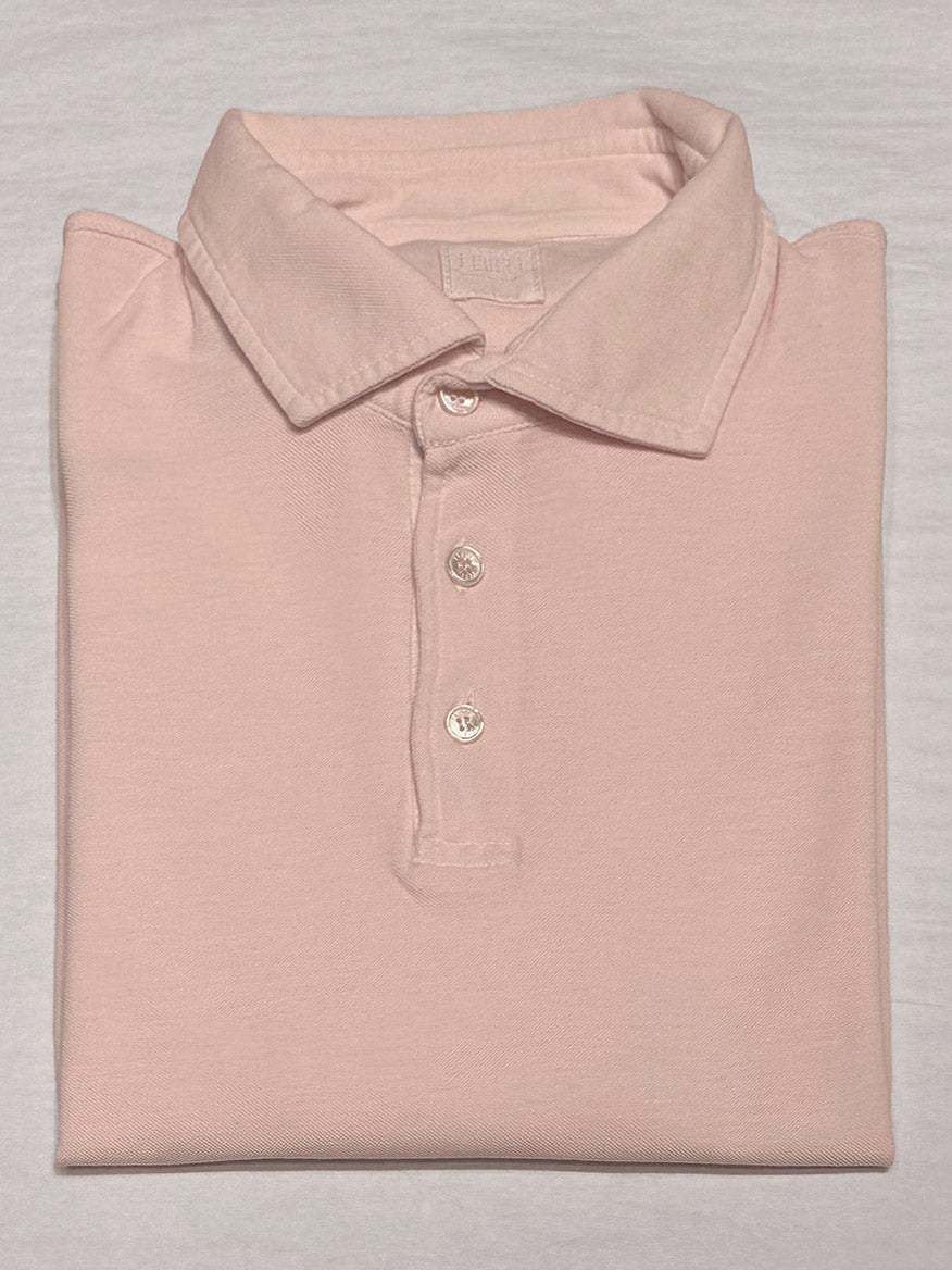 The Fedeli Zero Superlight Pique Short Sleeve Polo in Pink, featuring a vintage-inspired design with a collar and three buttons, is neatly folded on a flat, neutral background.