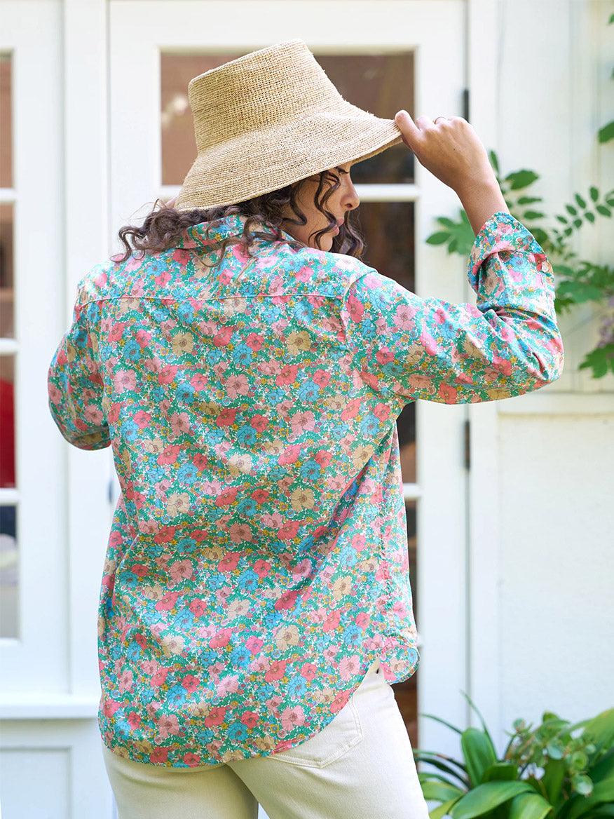 Person in a Frank & Eileen Eileen Relaxed Button-Up Shirt in Pink & Blue Floral made from Tana Lawn cotton and straw hat with their back to the camera.