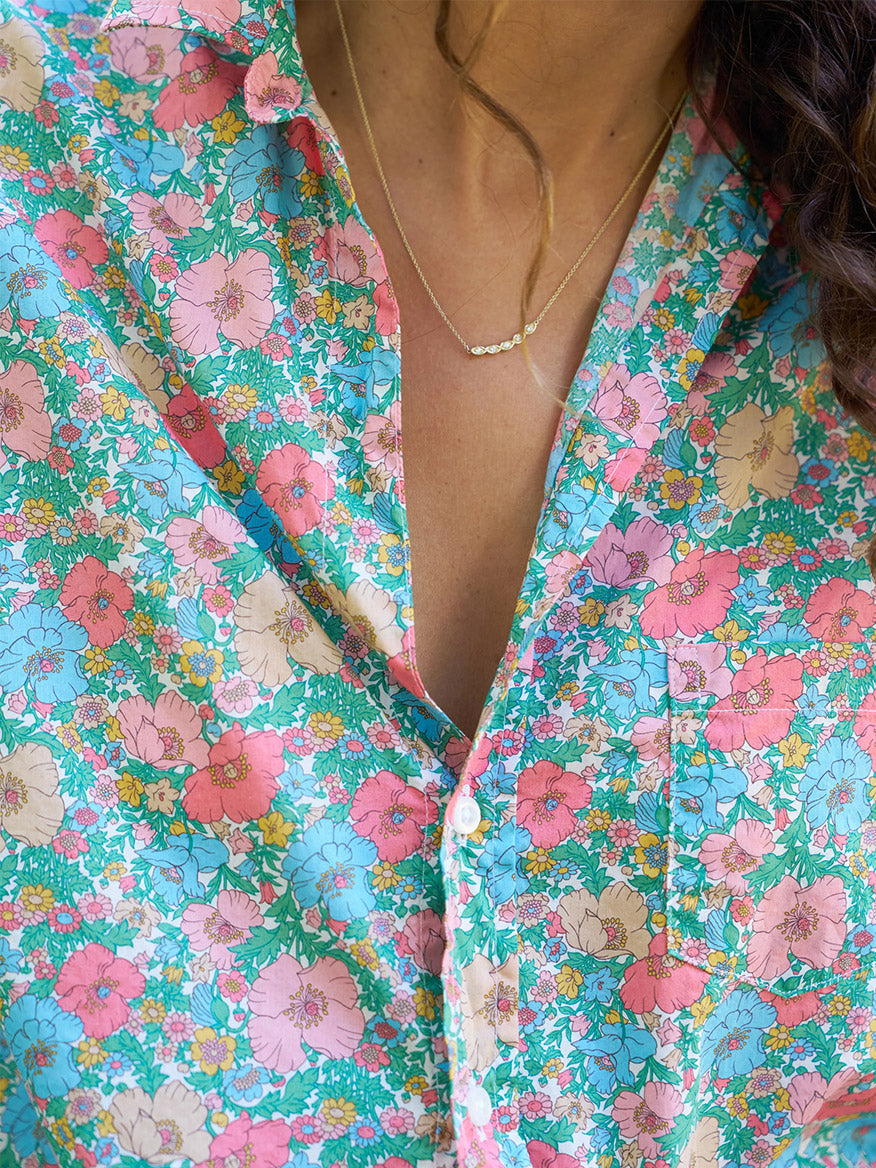 A close-up of a person wearing a Frank & Eileen Eileen Relaxed Button-Up Shirt in Pink & Blue Floral made from Tana Lawn cotton and a delicate necklace.