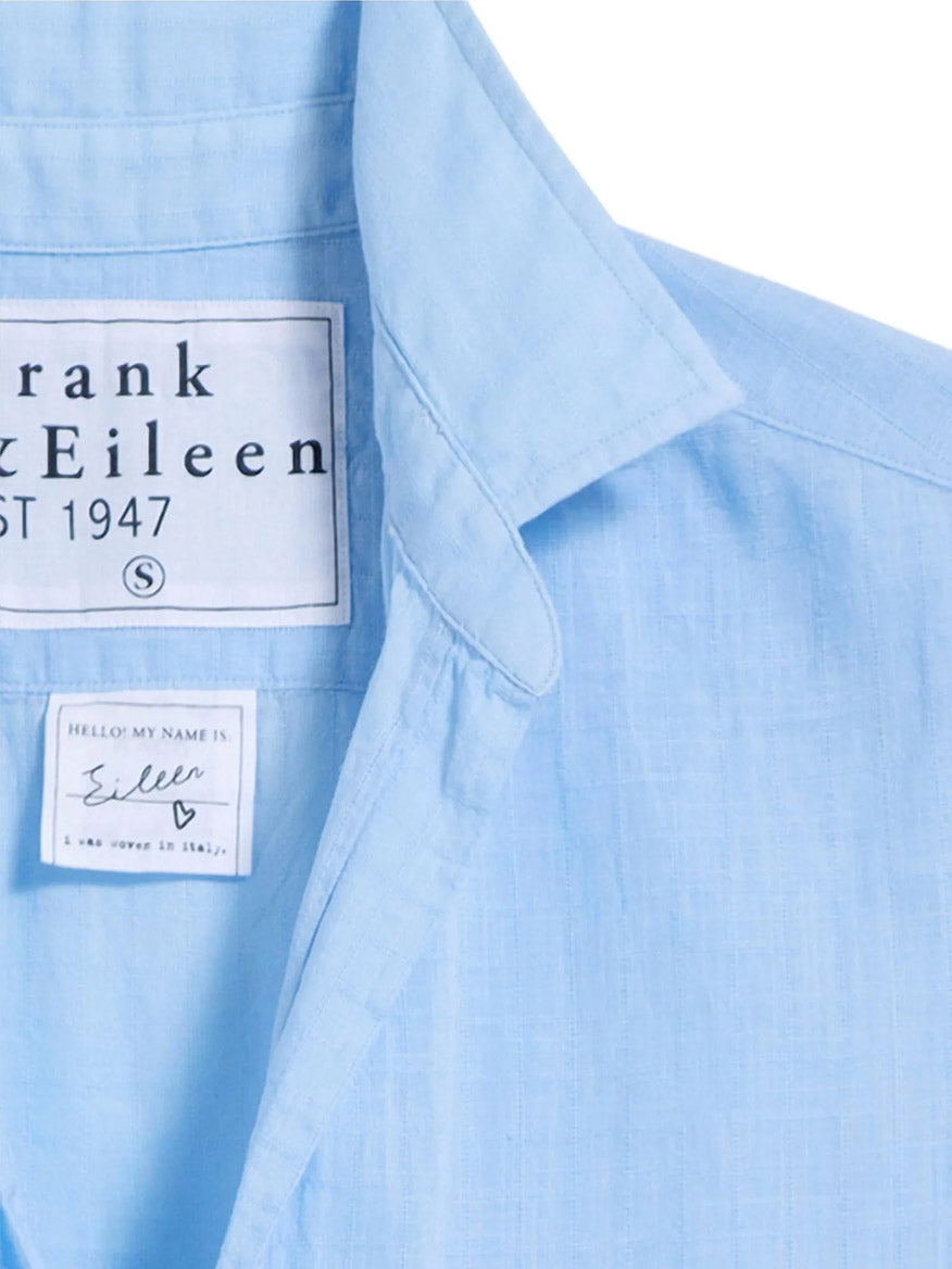 Close-up of the Frank & Eileen Eileen Relaxed Button-Up Shirt in Textured Blue, highlighting two labels: one displaying the "Frank & Eileen" brand and another with handwritten-style text reading "Hello my name is Eileen.