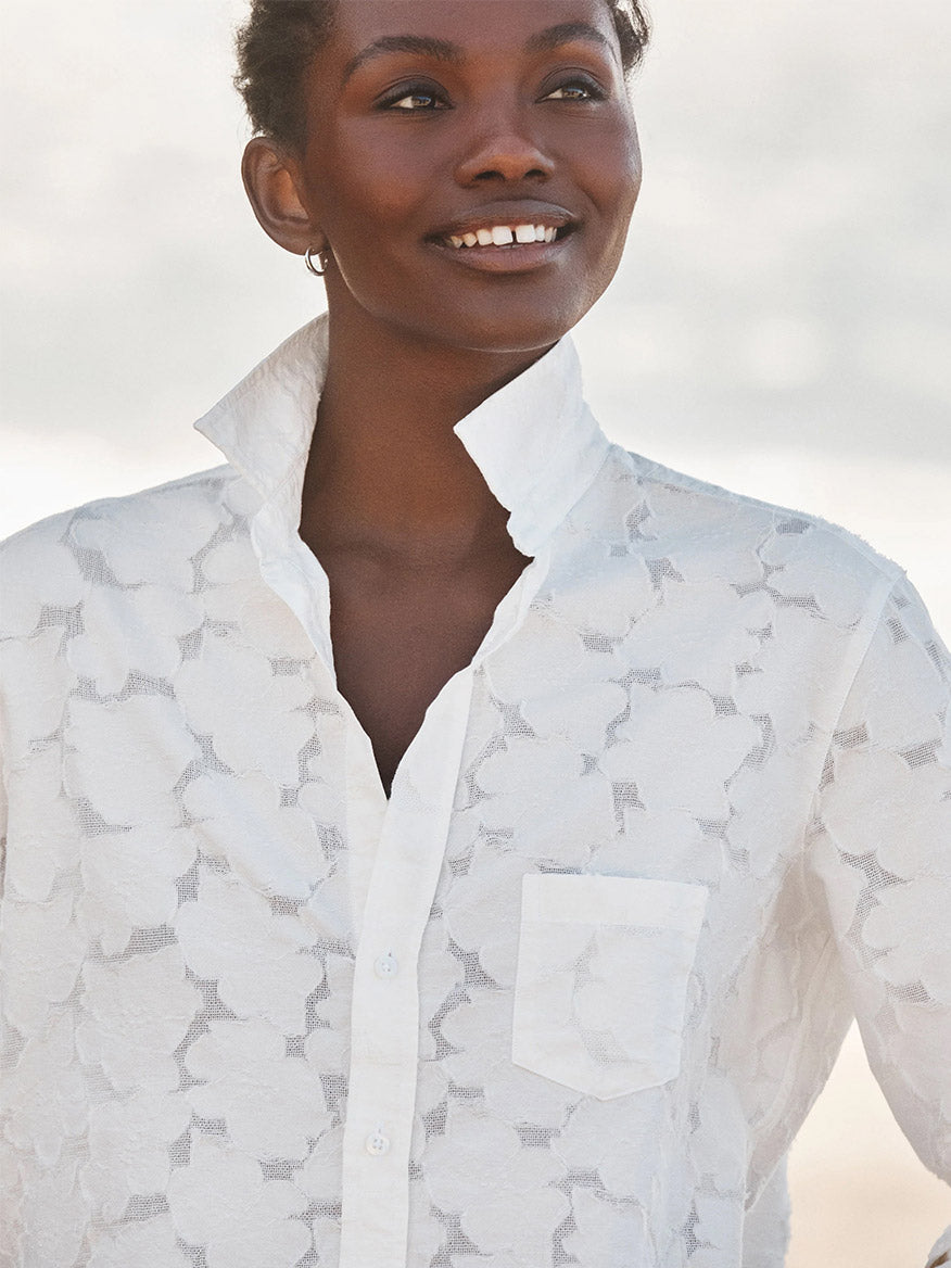 A person stands outdoors smiling, wearing the Frank & Eileen Eileen Relaxed Button-Up Shirt in Textured White Flowers with bust-flattering buttons and a popped collar.
