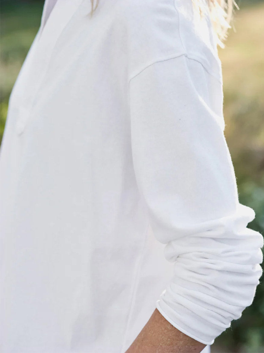 A close-up of a person wearing a Frank & Eileen Patrick Popover Henley in White Heritage Jersey with the sleeve scrunched up to the elbow.