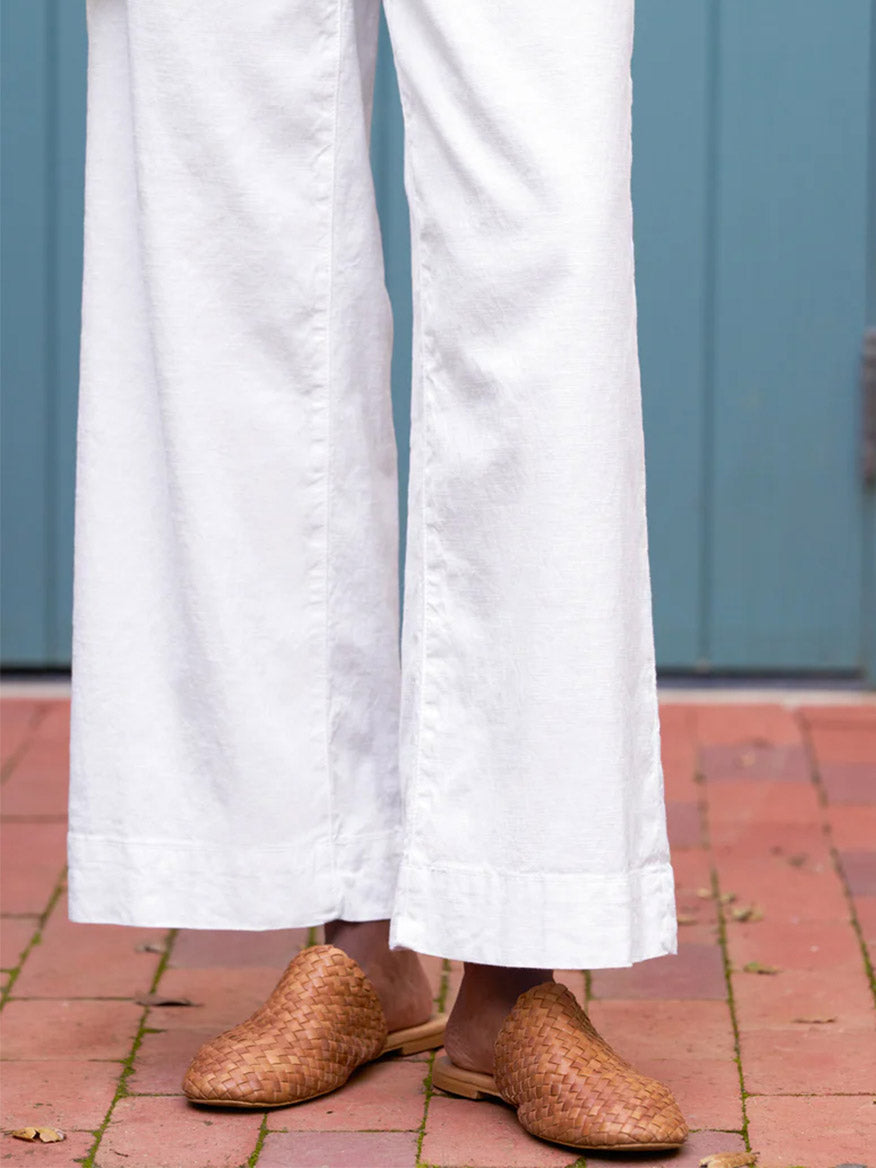A person wearing the Frank & Eileen Wexford Wide-Leg Linen Pant in White and tan woven loafers, standing on a brick surface.
