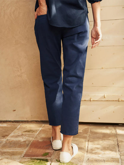 A woman standing in a courtyard wearing Frank & Eileen Wicklow Italian Chino in Vintage Navy with a matching top, paired with white slip-on shoes.