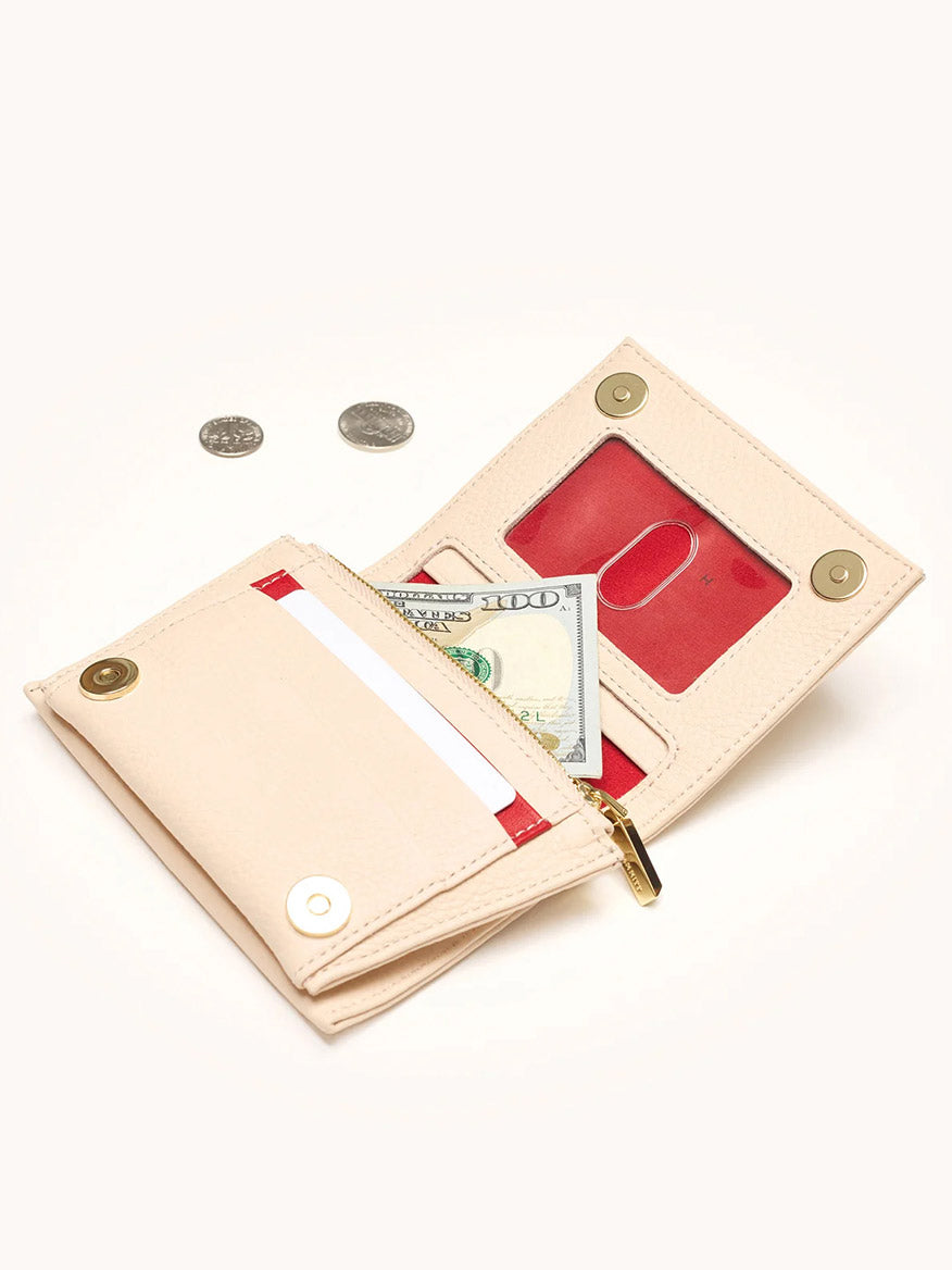 A Hammitt Los Angeles Allen Wallet in Superbloom Pink, crafted from pebbled leather, is open to display a hundred dollar bill, card slot, ID window, and two coins placed beside it.