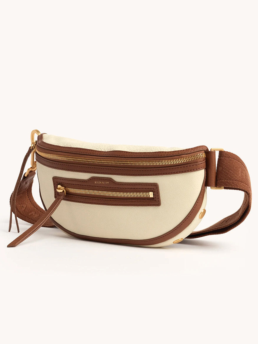 The Hammitt Los Angeles Charles Crossbody Medium in Courtyard Cream features beige and brown pebbled leather, gold zippers, and a front zip pocket, shown against a plain background.