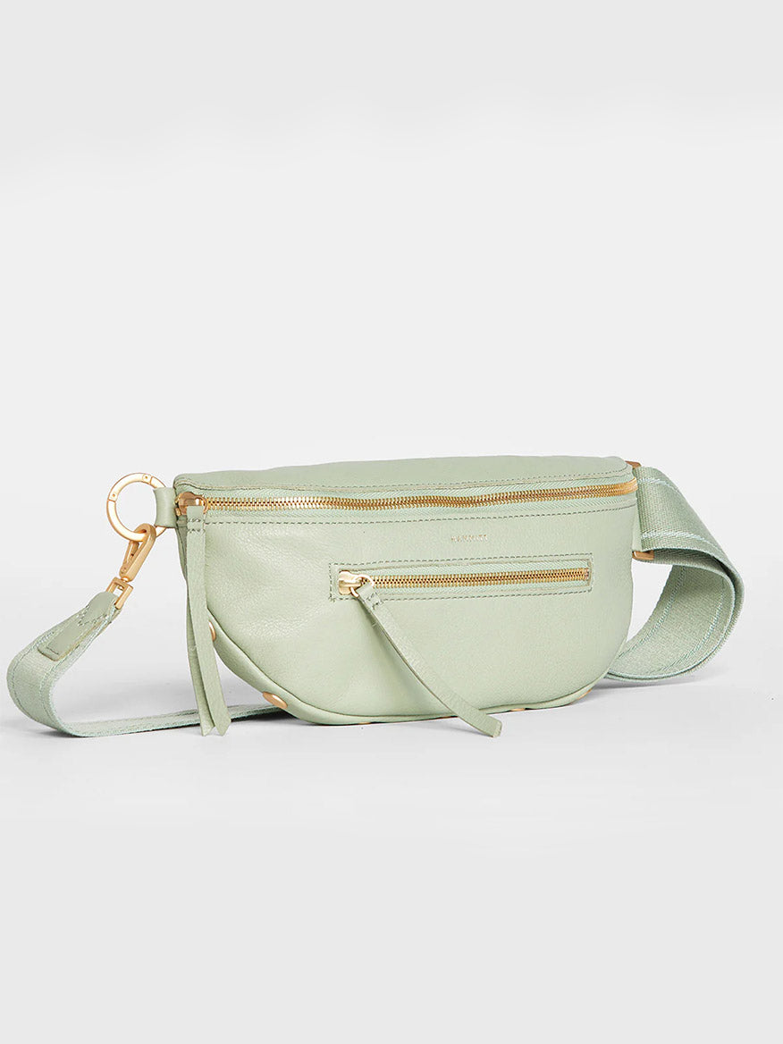 Hammitt Los Angeles Charles Crossbody Medium in Cypress Sage pale green crossbody bag with two exterior zippers, a gold-toned hardware clasp, and an adjustable strap, against a plain background.