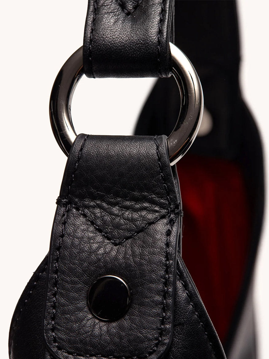 Close-up of the Hammitt Los Angeles Tim Hobo in Black, showcasing its pebbled leather strap with visible stitching, shiny metal ring, and snap button—an elegant detail to elevate your favorite accessory.