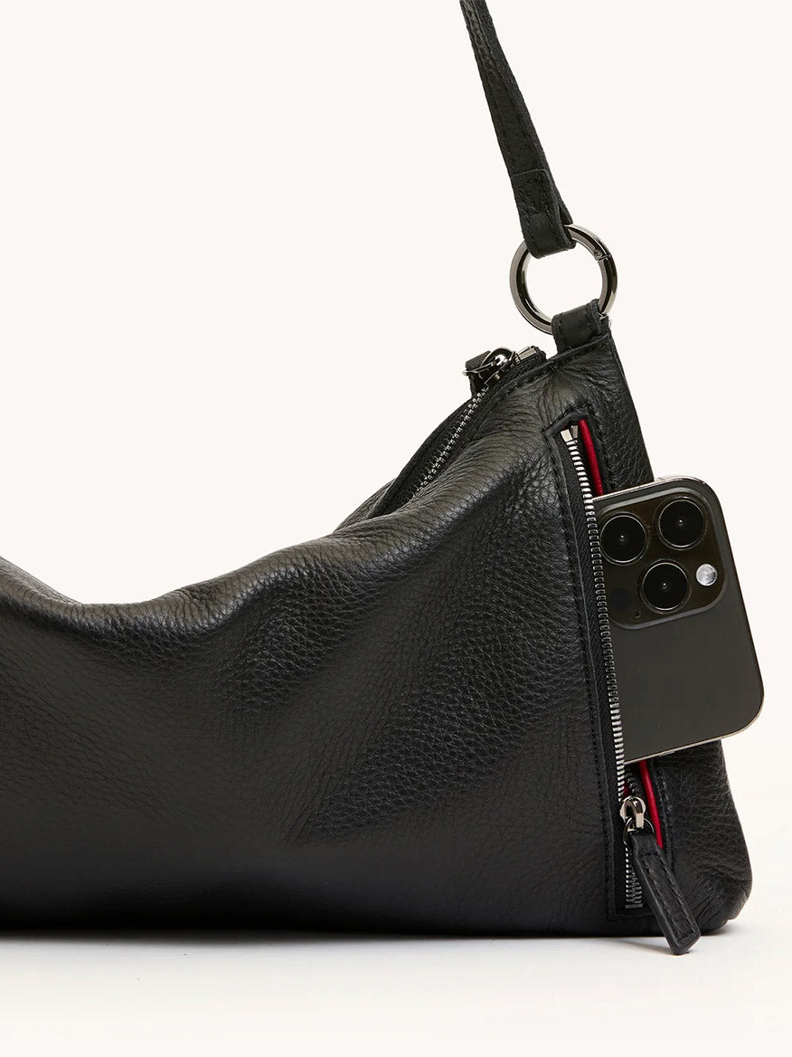 The Hammitt Los Angeles Kyle Medium Shoulder Bag in Black/Gunmetal features black pebble leather, a visible zipper pocket—partially unzipped to show a smartphone—and can be worn as both a crossbody and shoulder bag.