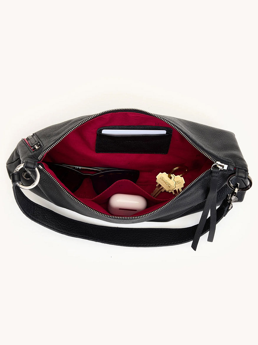 The Hammitt Los Angeles Kyle Medium Shoulder Bag in Black/Gunmetal, shown open with a red interior, fits sunglasses, a keychain, a small white case, and more; can be worn as both a crossbody and shoulder bag.