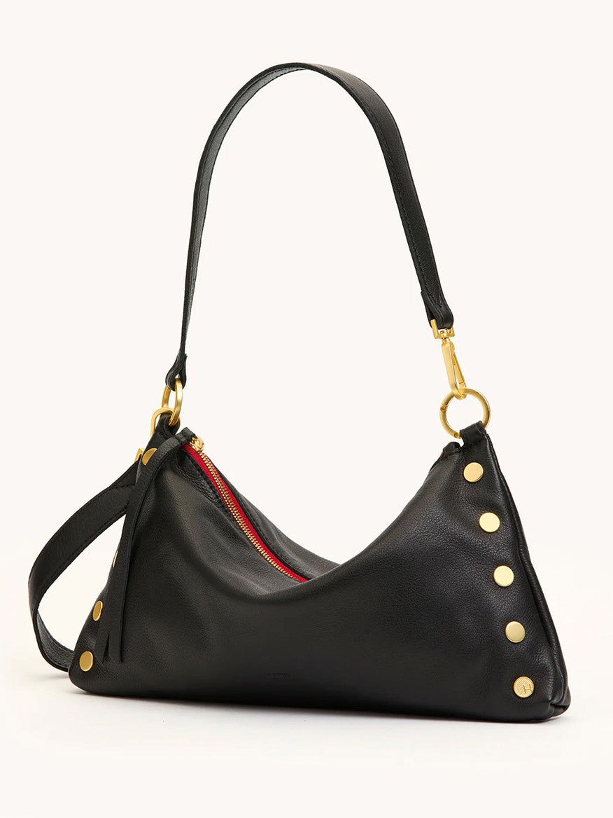 The Hammitt Los Angeles Kyle Medium Shoulder Bag in Black/Brushed Gold/Red Zip features black pebble leather, gold side studs, a red zipper, and a detachable strap for easy transition between crossbody and shoulder styles.