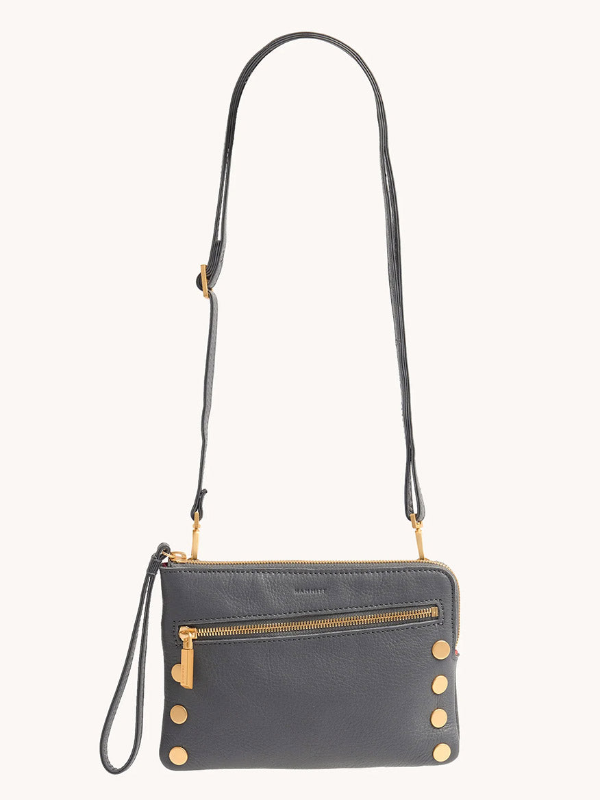 The Hammitt Los Angeles Nash Small Clutch in Sonnet Grey/Brushed Gold is a compact dark gray pebbled leather bag with gold hardware, a front zipper pocket, adjustable strap, and six gold studs at the bottom corners.