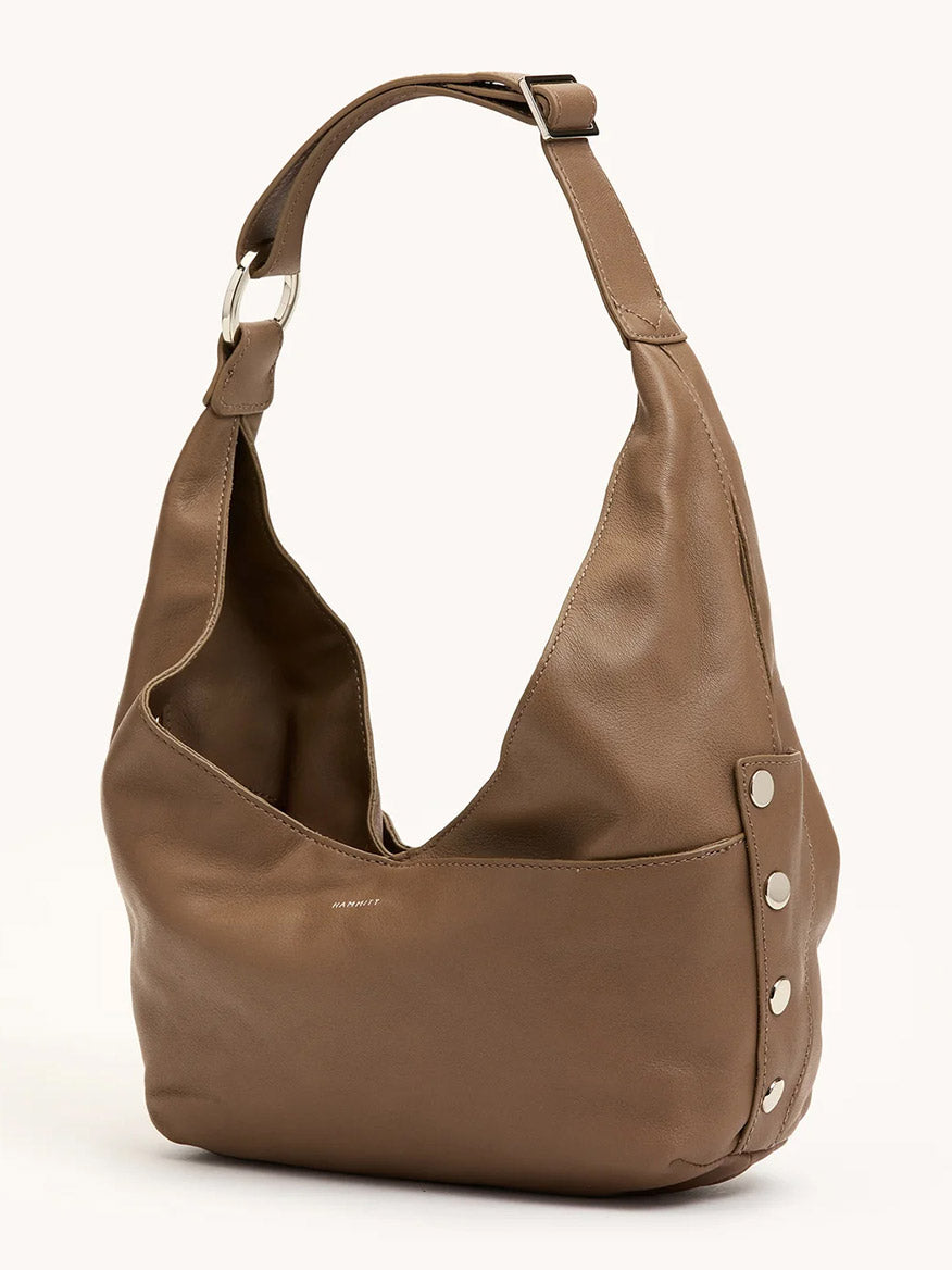 The Hammitt Los Angeles Tom Zip Medium in Dune/Silver is a brown leather hobo bag featuring a wide adjustable strap with silver buckle, metal rivet accents on the sides, and a zippered main compartment, shown against a plain background.