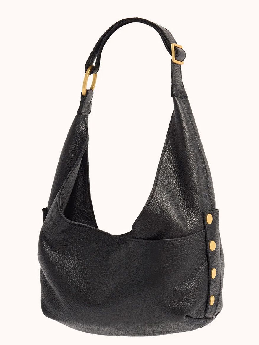 The Hammitt Los Angeles Tom Zip Medium in Black/Brushed Gold & Red Zip is a black pebbled leather shoulder bag with gold-tone hardware, a single wide adjustable strap, and a slouchy, textured design.