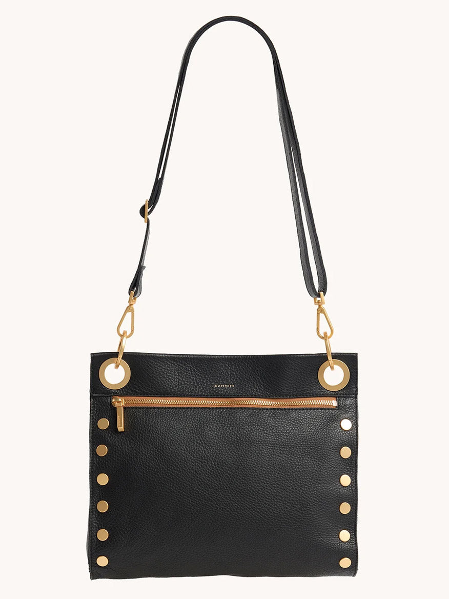 The Hammitt Los Angeles Tony Large Crossbody Bag in North End features black leather, gold-tone hardware with large grommets and side studs, an adjustable strap, and a front zip pocket, shown against a plain background.