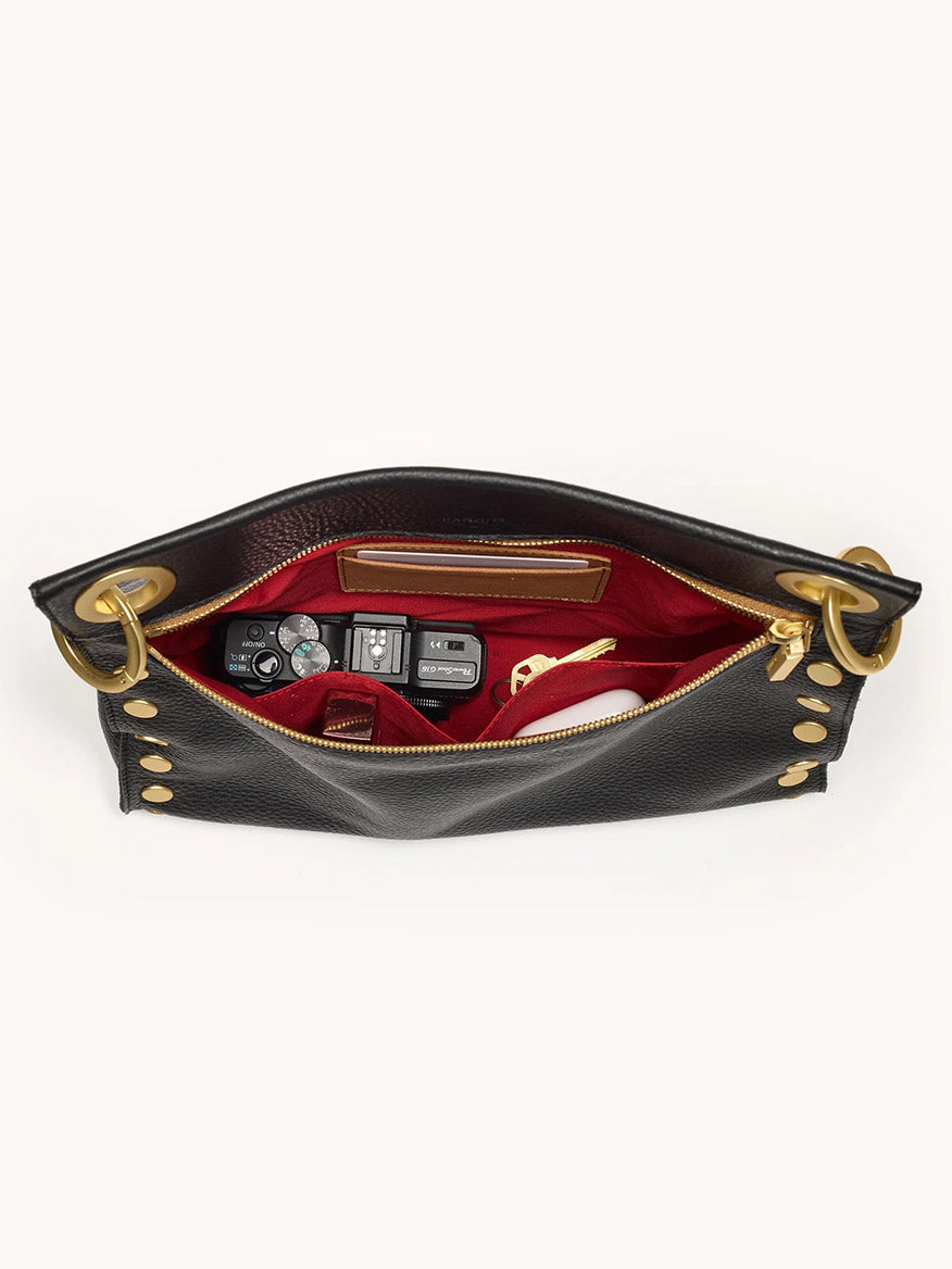 The Hammitt Los Angeles Tony Large Crossbody Bag in North End is an open black leather bag with gold hardware, showing a red interior that fits a camera, phone, and glasses.