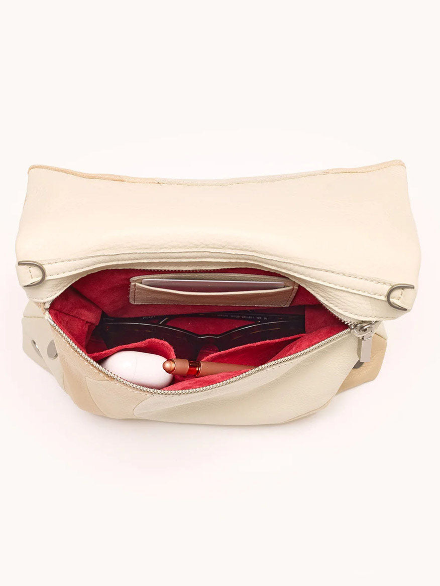 The Hammitt Los Angeles VIP Medium Clutch in Coastal Cream/Brushed Silver is shown open, revealing a red interior with sunglasses, a white item, and small accessories neatly arranged in separate compartments.