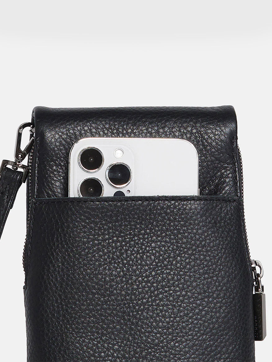 A Hammitt Los Angeles VIP Mobile in Black/Gunmetal peeks out from the front pocket of a black crossbody bag with a zipper and textured pebbled leather.