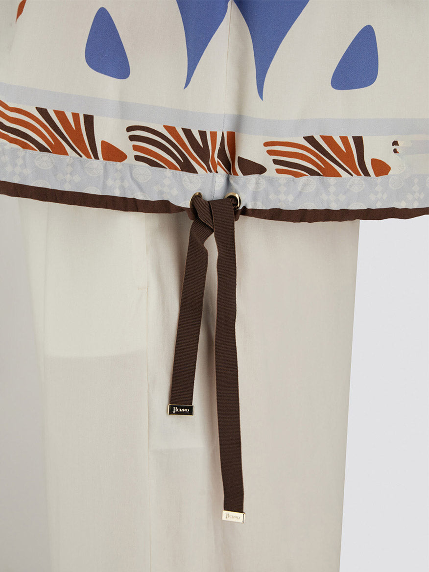 Close-up of the Herno Summer Print Cotton Top in multicolor, featuring a patterned hem with brown drawstring and gold metal tips, styled over white pants. Made in Italy.