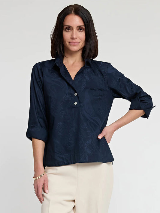 A woman posing in a Hinson Wu Aileen Button Back Top in Navy Bali Jacquard with a subtle pattern, paired with light-colored stretch polished cotton pants.