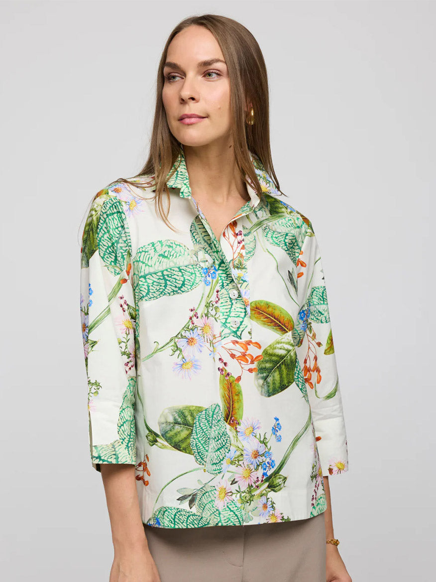 A person wearing the Hinson Wu Aileen 3/4 Sleeve Botanical Flora Print Shirt in Multi stands against a plain background, showcasing its exclusive floral-patterned design with green leaves and colorful flowers on refined cotton.