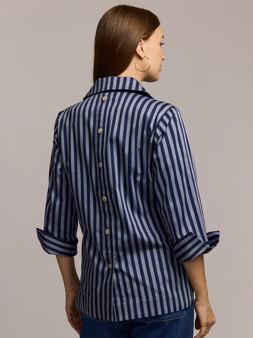 A woman faces away, wearing the Hinson Wu Aileen 3/4 Sleeve Classic Stripe Shirt in French Grey/Midnight, a relaxed fit cotton button-down with vertical stripes, back buttons, and rolled sleeves.