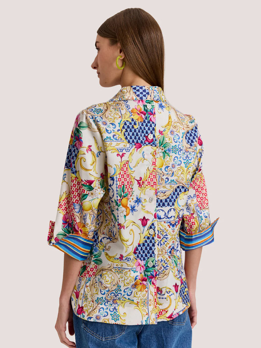 A woman with straight brown hair is seen from behind, wearing the Hinson Wu Aileen 3/4 Sleeve Amalfi Print Top and blue jeans.